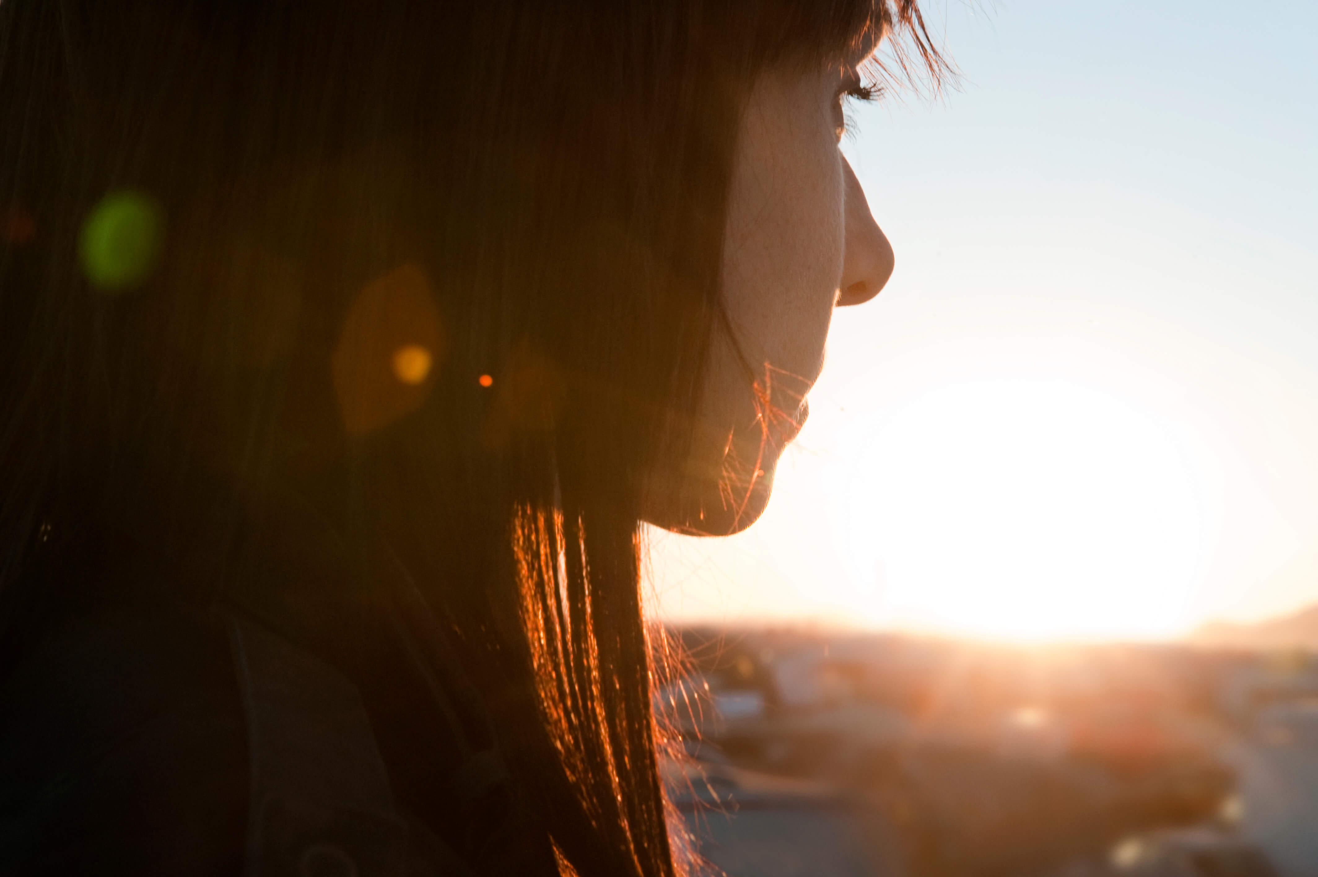 A side profile of a person looking into the sunset