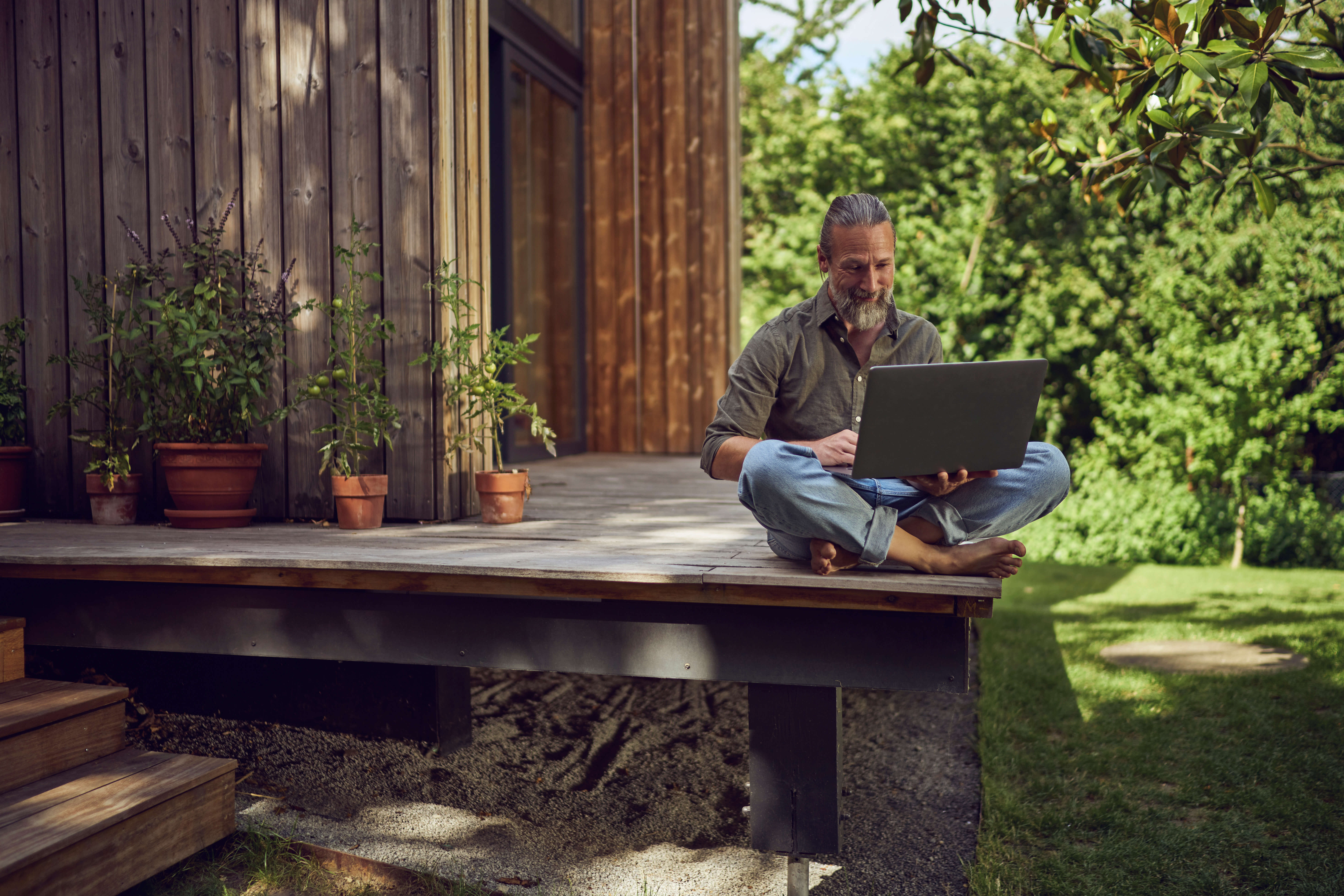 A person in a garden looking at a laptop