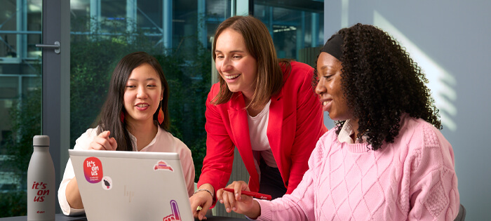 Three friends looking at a computer screen, smiling