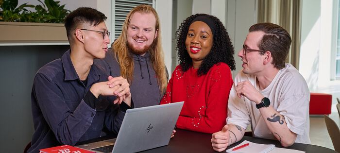 A group of people chatting together around a laptop