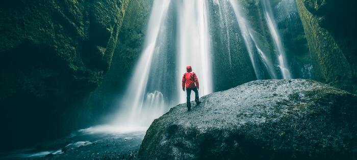A person stands watching a waterfall